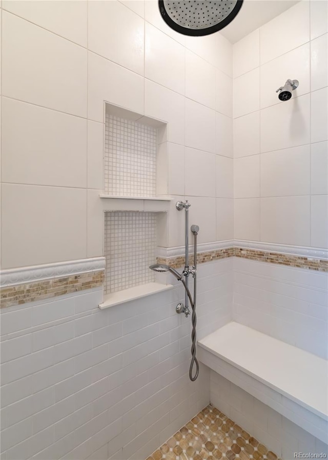 full bathroom with tile patterned floors, tile walls, and a tile shower