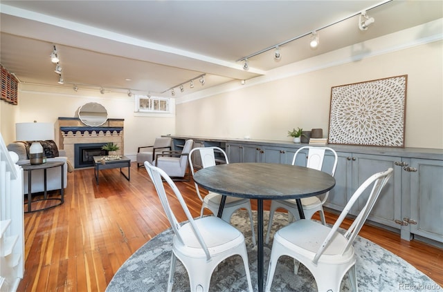dining area featuring track lighting, light wood-style floors, and a fireplace