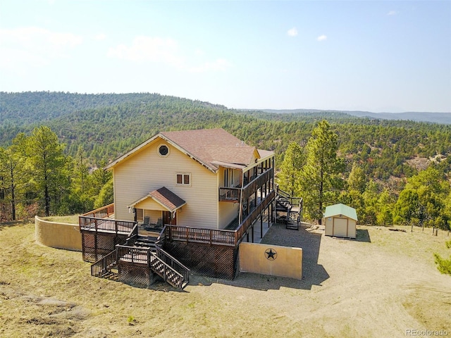 rear view of house with a deck and a shed