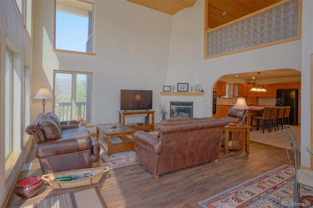 living room with hardwood / wood-style floors, wooden ceiling, a high ceiling, and a fireplace