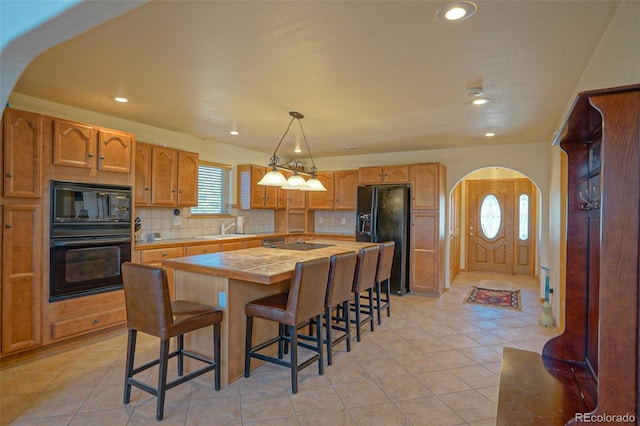 kitchen featuring a kitchen island, tasteful backsplash, black appliances, and sink