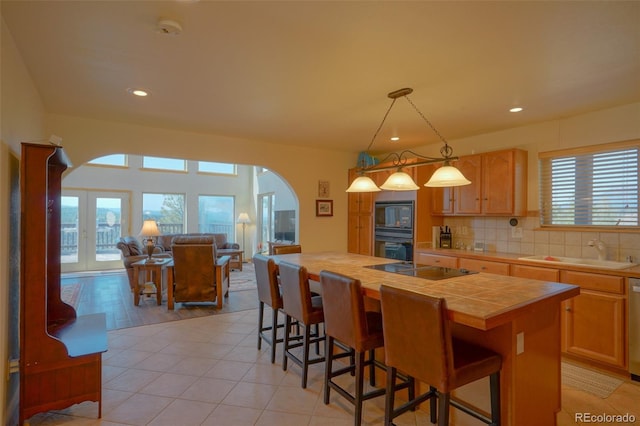 kitchen with a kitchen island, sink, backsplash, hanging light fixtures, and plenty of natural light