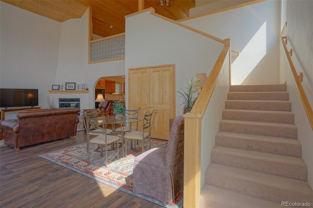 staircase featuring dark wood-type flooring, a towering ceiling, and a fireplace