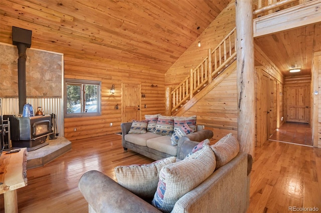 living room featuring wood ceiling, high vaulted ceiling, light hardwood / wood-style flooring, a wood stove, and wood walls