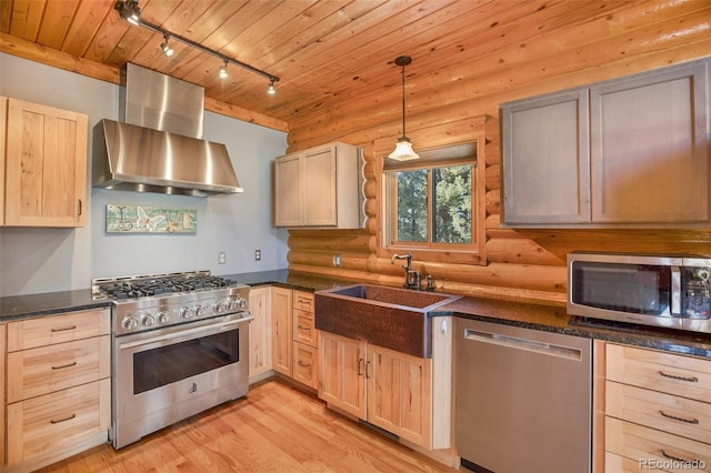 kitchen featuring rustic walls, light brown cabinets, wall chimney exhaust hood, stainless steel appliances, and light hardwood / wood-style floors