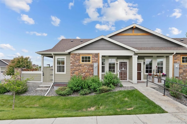 12940 Jasmine St Unit A, Thornton, CO 80602 - view of front of property featuring stone siding, a front lawn, roof with shingles, and a porch