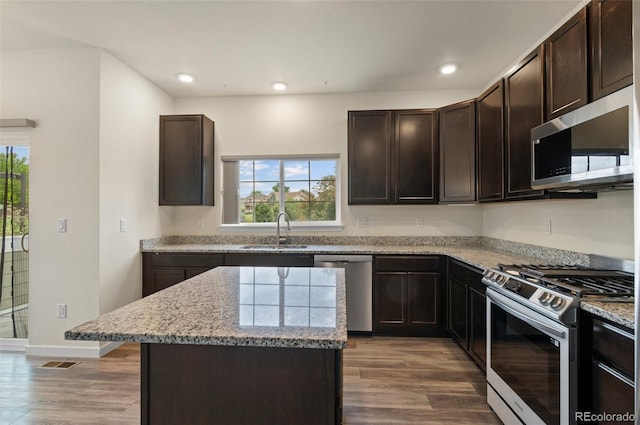 12940 Jasmine St Unit A, Thornton, CO 80602 - kitchen with stainless steel appliances, a sink, wood finished floors, light stone countertops, and dark brown cabinetry