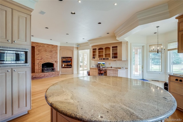 kitchen featuring a large island, stainless steel microwave, light stone counters, and open shelves