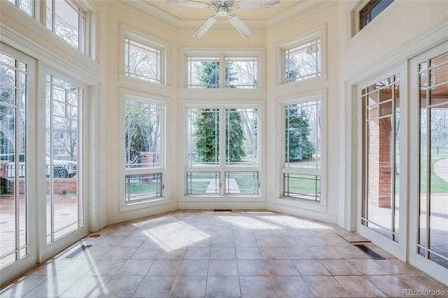 unfurnished sunroom featuring ornamental molding, a healthy amount of sunlight, and a towering ceiling