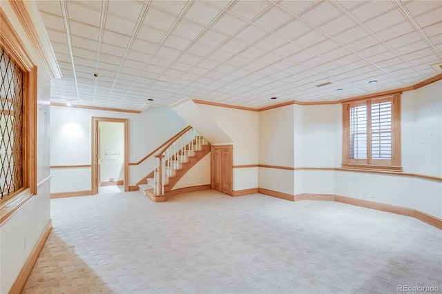 unfurnished room featuring stairway, light carpet, crown molding, and baseboards