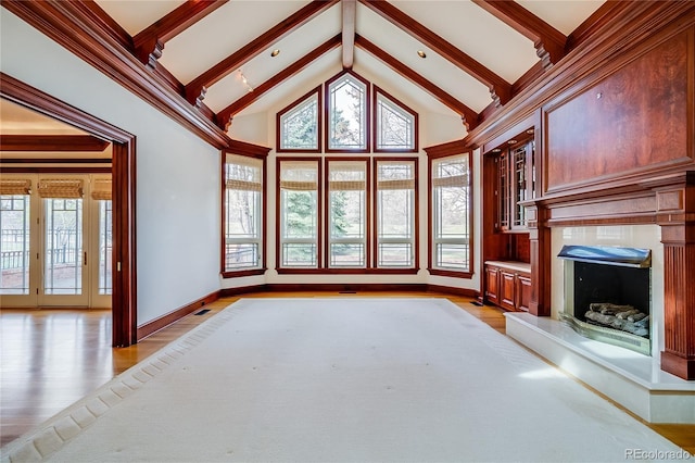 unfurnished living room with baseboards, light wood-style flooring, beam ceiling, and high vaulted ceiling