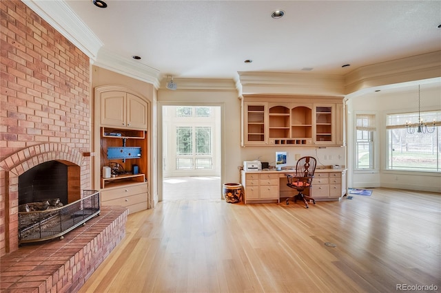 interior space with light wood finished floors, a brick fireplace, crown molding, and a notable chandelier