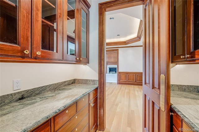 bathroom featuring wainscoting, wood finished floors, a decorative wall, vanity, and ornamental molding