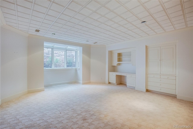 interior space featuring built in study area, crown molding, baseboards, and light carpet