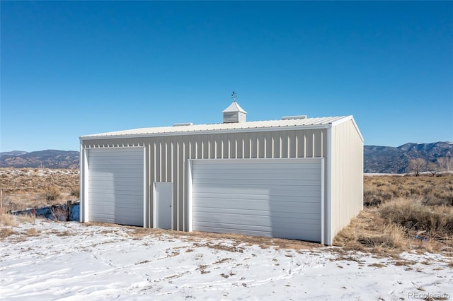 snow covered garage featuring a mountain view