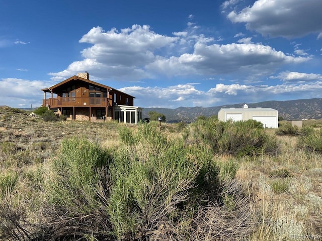 20155 Hideout Ln, Nathrop, CO 81236 - back of house with a chimney, a deck with mountain view, and an outbuilding