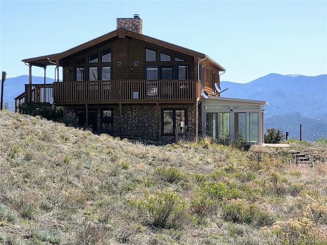 20155 Hideout Ln, Nathrop, CO 81236 - back of house with a chimney, stone siding, a deck with mountain view, and a sunroom