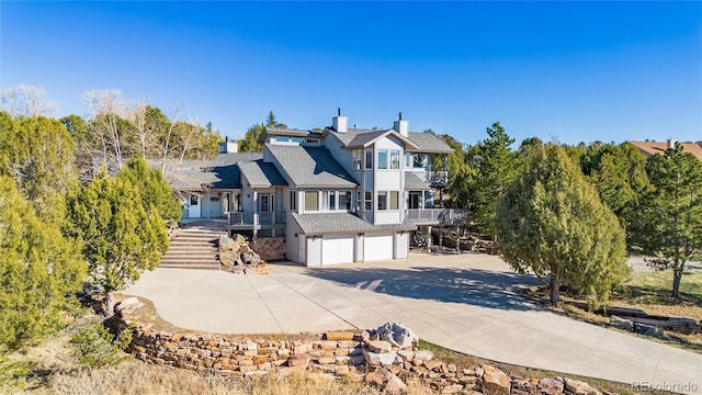 249 Valle Escondido Dr, Durango, CO 81303 - view of front of home with a balcony, a chimney, an attached garage, stairs, and concrete driveway