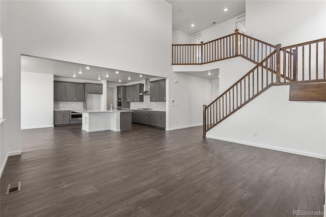 unfurnished living room featuring dark hardwood / wood-style flooring, a towering ceiling, and sink