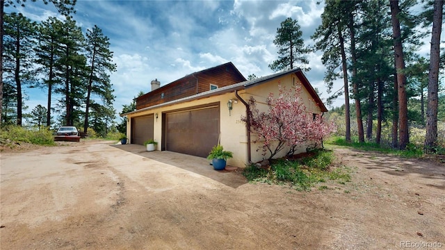 2545 N State Highway 67, Sedalia, CO 80135 - view of property exterior with a chimney, stucco siding, an attached garage, and driveway