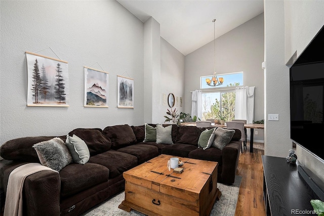 living room with a chandelier, high vaulted ceiling, and wood finished floors