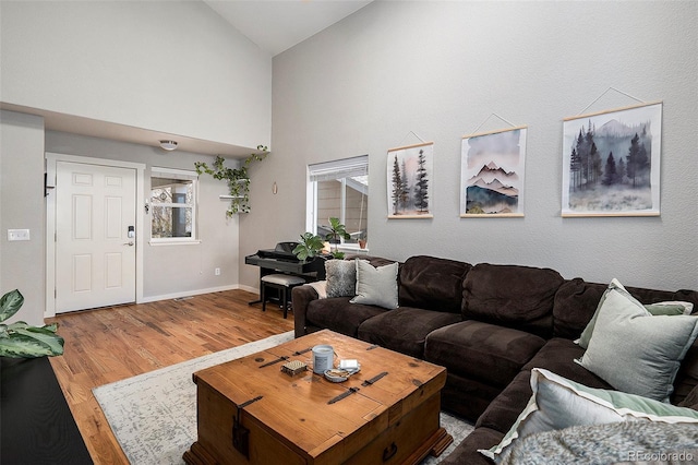 living room with high vaulted ceiling, baseboards, and wood finished floors