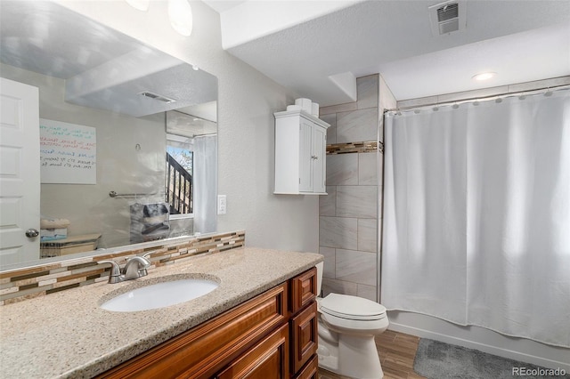 bathroom featuring tasteful backsplash, visible vents, toilet, and wood finished floors