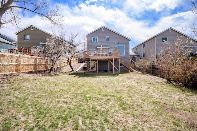 rear view of house featuring a fenced backyard, stairway, a deck, and a lawn