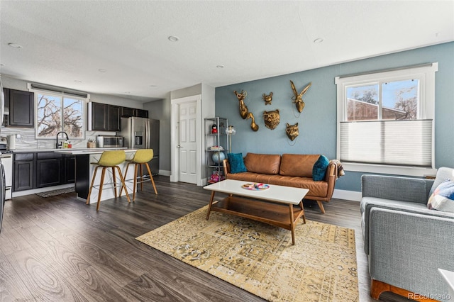 living room featuring dark wood-style floors, a wealth of natural light, a textured ceiling, and baseboards