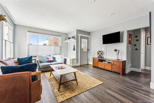 living area with a textured ceiling, dark wood-style flooring, and baseboards