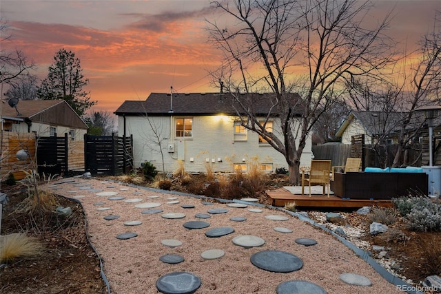 exterior space with a deck, brick siding, a shingled roof, and fence