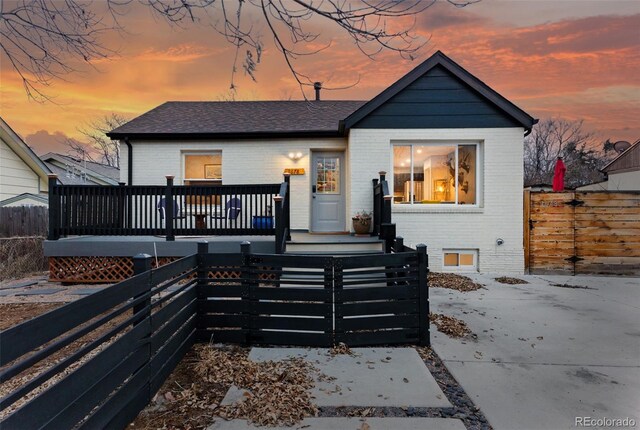 view of front of house featuring fence private yard, a shingled roof, a deck, and brick siding