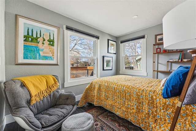 bedroom featuring a textured wall, baseboards, and wood finished floors