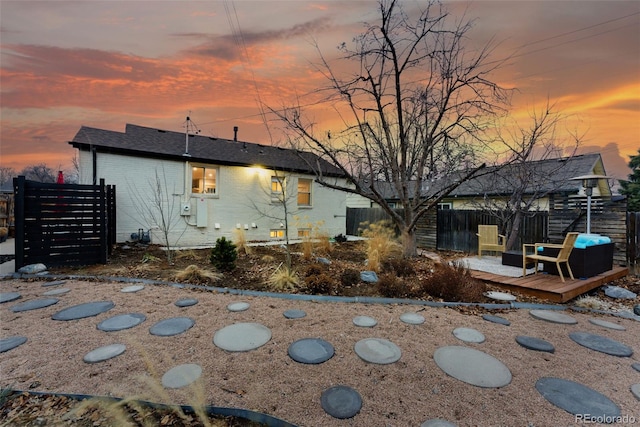 back of house at dusk with brick siding, fence, and a wooden deck