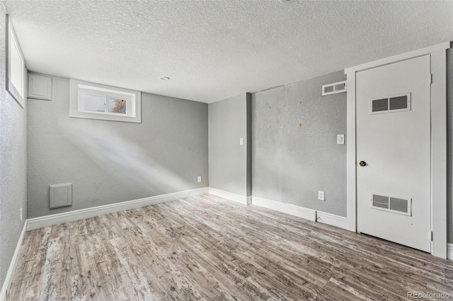 unfurnished room featuring baseboards, visible vents, and wood finished floors