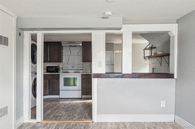 kitchen featuring stacked washing maching and dryer, wood finished floors, white electric range oven, and dark brown cabinetry