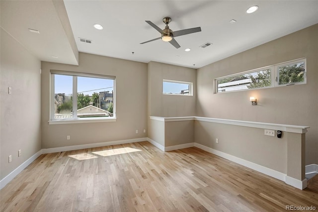 empty room featuring ceiling fan, a healthy amount of sunlight, and light hardwood / wood-style flooring