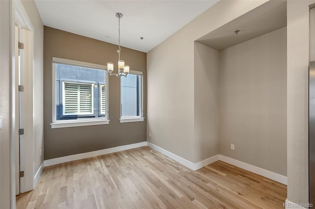 unfurnished dining area with light hardwood / wood-style floors and an inviting chandelier