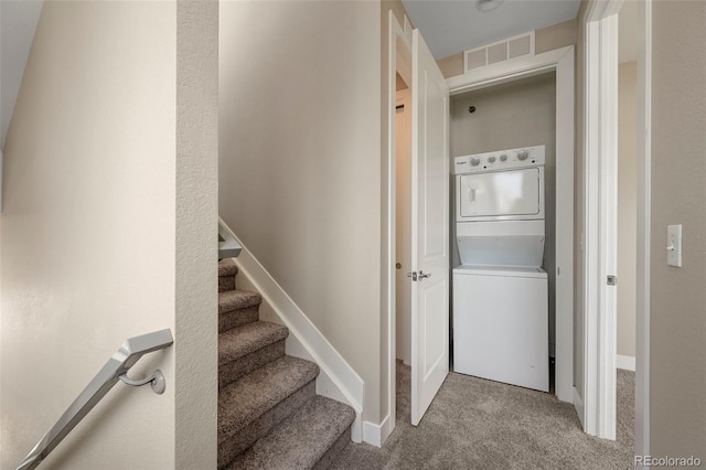 stairway with carpet floors and stacked washer / drying machine