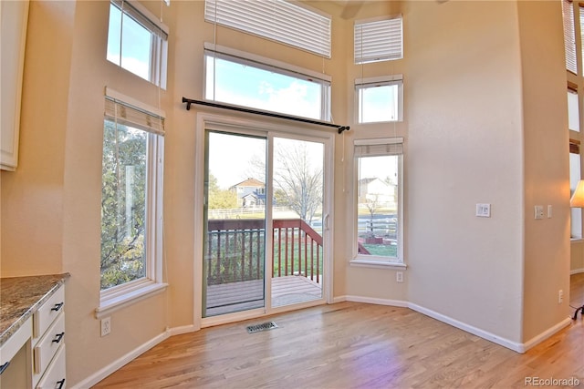 entryway with light hardwood / wood-style flooring and a towering ceiling