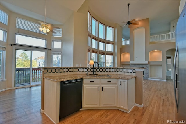 kitchen featuring white cabinets, a towering ceiling, black dishwasher, and tasteful backsplash