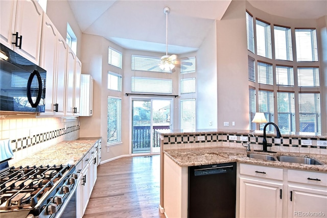 kitchen featuring sink, light stone counters, decorative backsplash, white cabinets, and black appliances