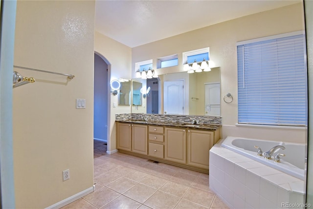 bathroom with tile patterned flooring, vanity, and tiled tub