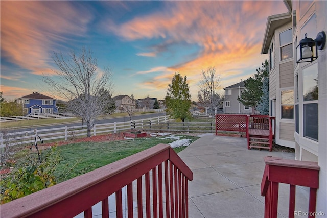 patio terrace at dusk featuring a yard