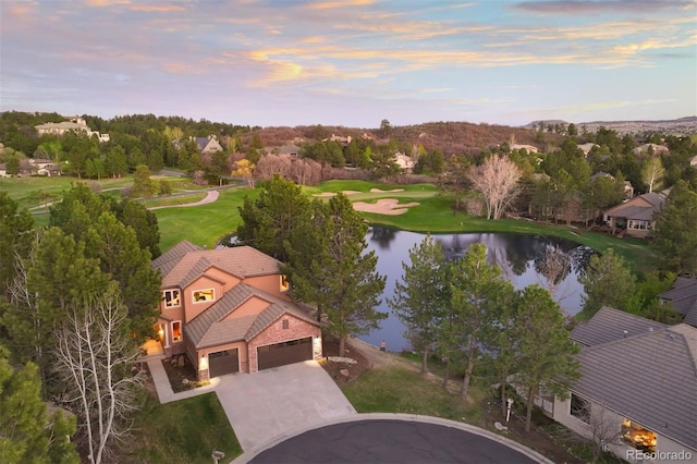 aerial view at dusk of a water view and view of golf course