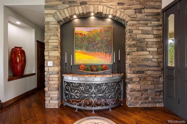 detailed view of wood finished floors, baseboards, and arched walkways