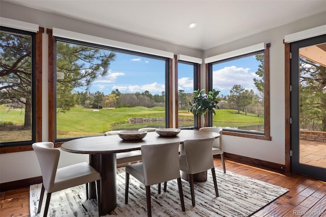 dining space with baseboards, hardwood / wood-style floors, recessed lighting, golf course view, and view of scattered trees
