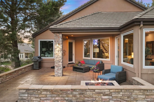 back of house featuring a patio, a tiled roof, an outdoor living space with a fire pit, and stucco siding