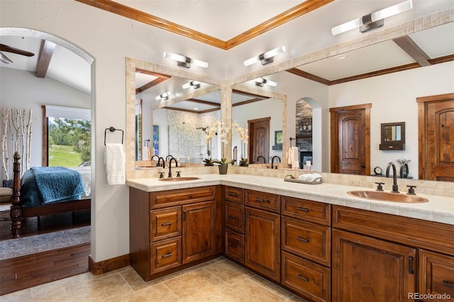 ensuite bathroom featuring double vanity, ornamental molding, and a ceiling fan