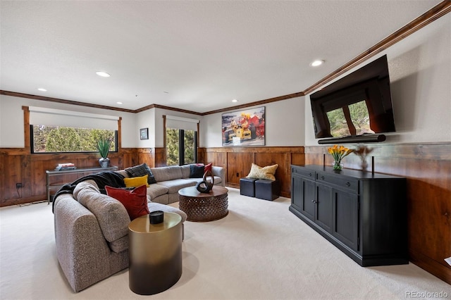living room featuring a wainscoted wall, light colored carpet, recessed lighting, crown molding, and wood walls